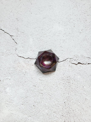 Top view of a hexagonal dice pedestal. It's black base beneath a color shifting combination of purples, golds, and reds