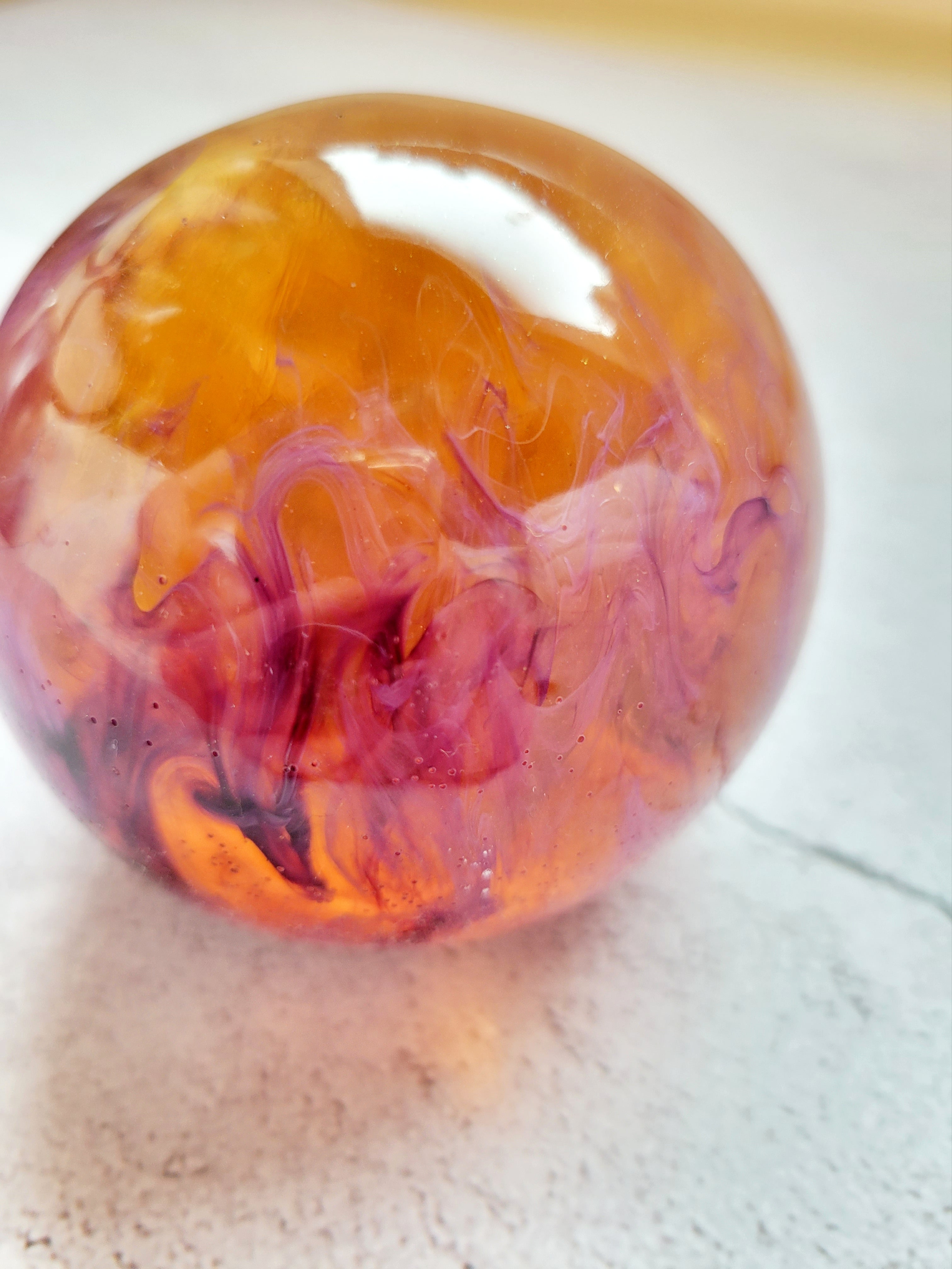 large resin ball with yellow and purple ink swirls. side View