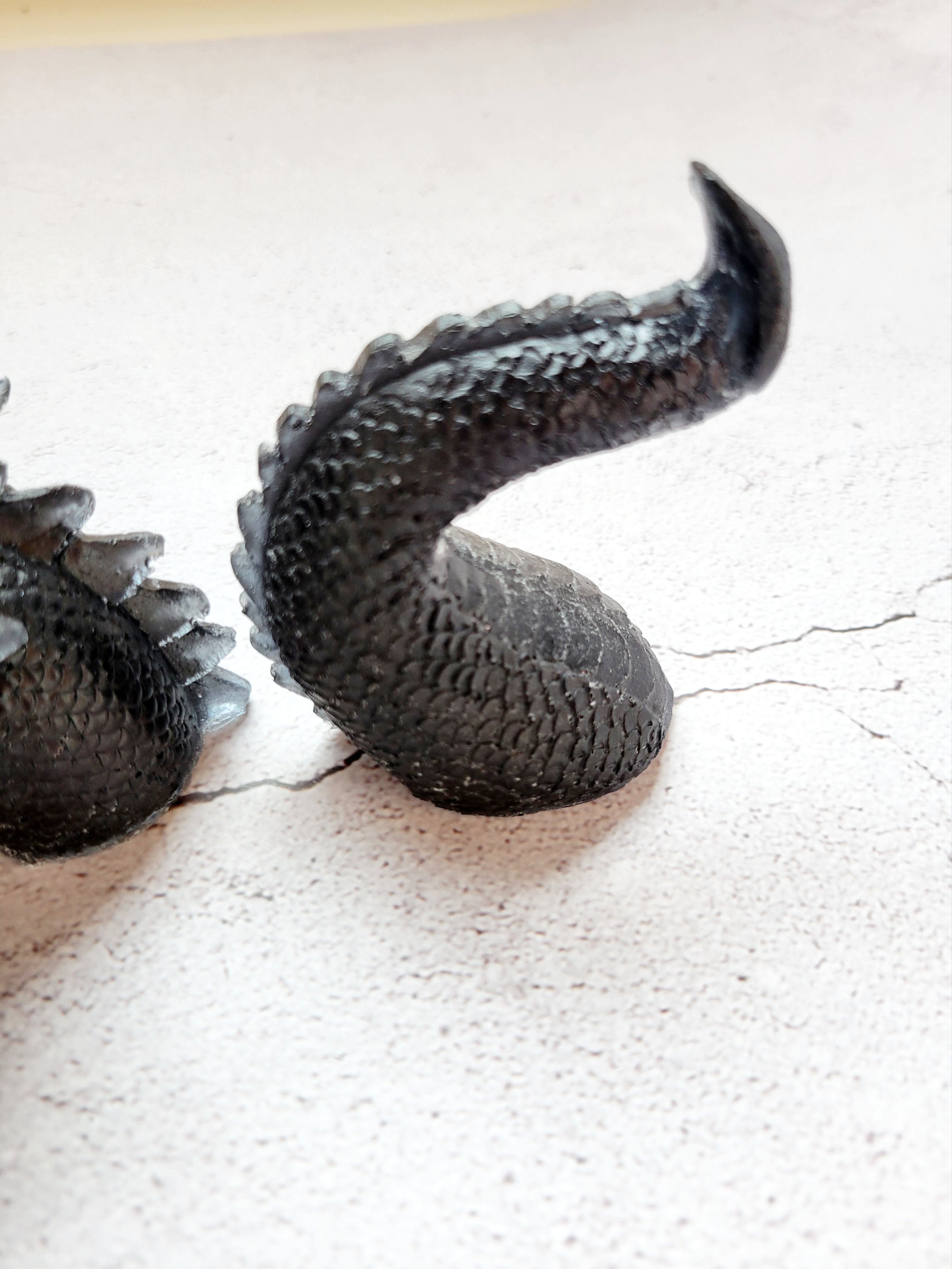 curved tail of black resin sea serpent