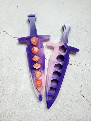 resin dice dagger, open with dice inside. It's dark purple and light pink swirled together. Top view