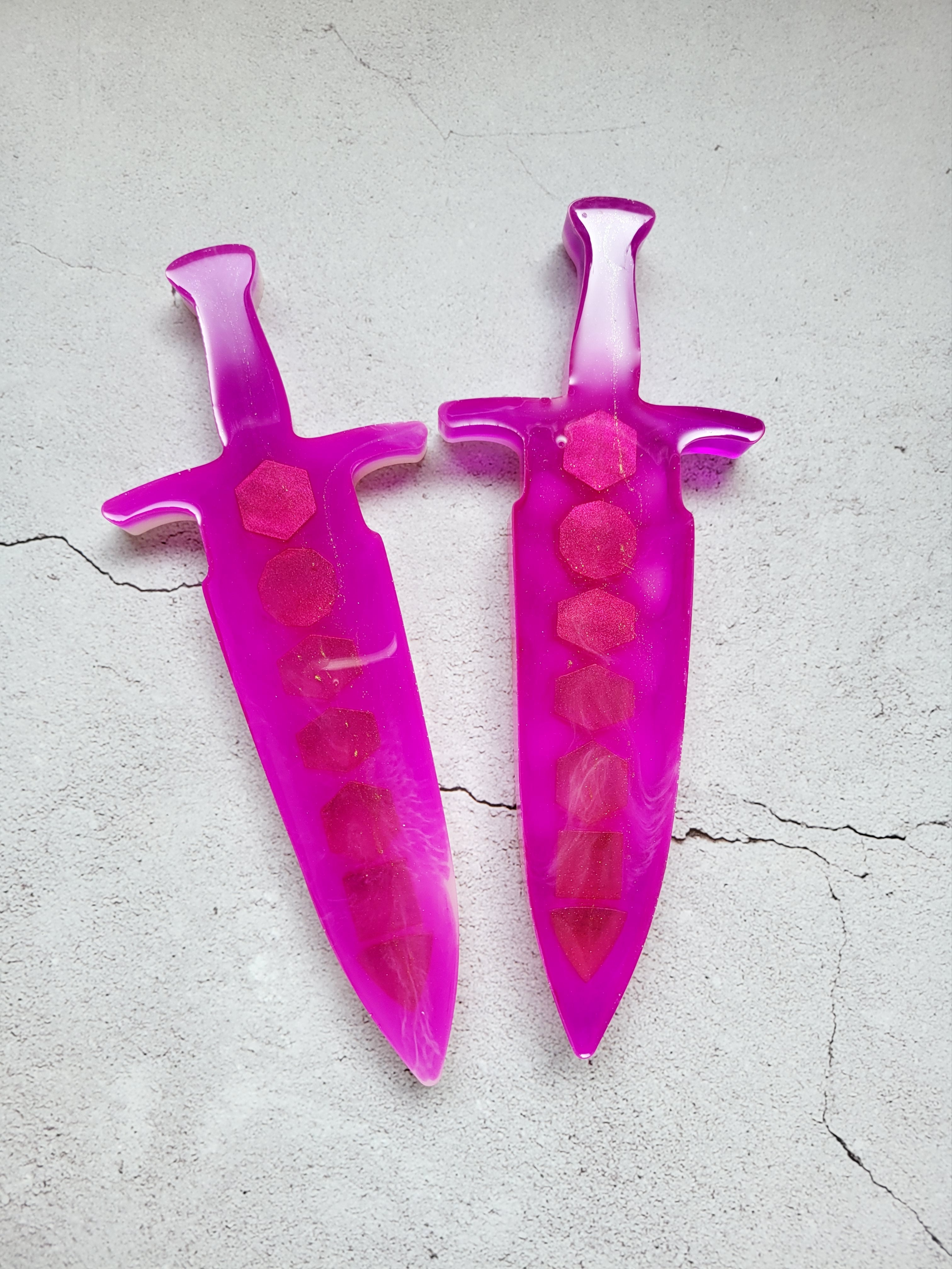 resin dice dagger. It's outside is bright pink, the inside is white with gold spray. Back view