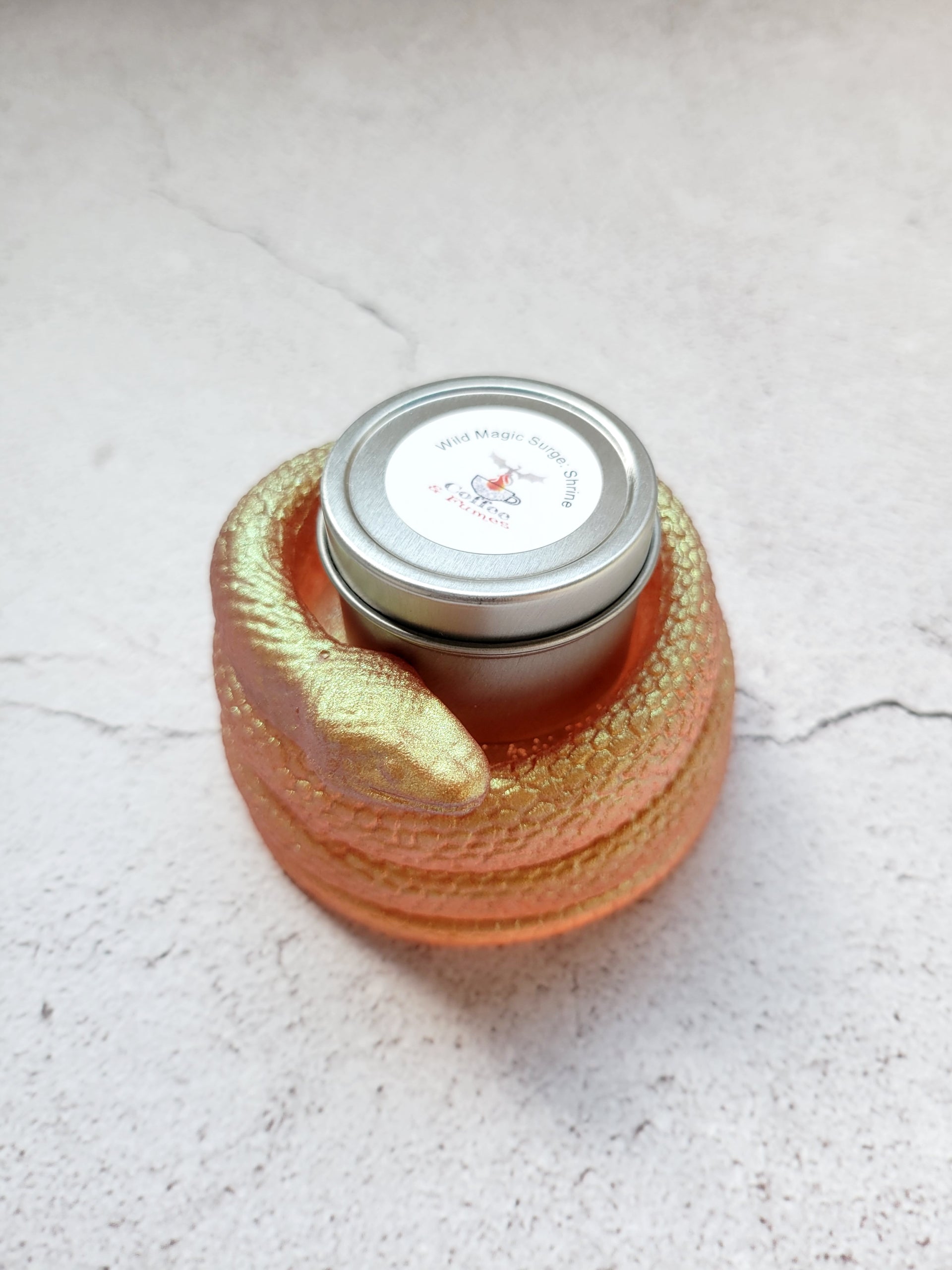 A side view of a tealight candle holder in the style of a coiled snake. It's a shimmering gold color. It has a tealight candle inside to show size comparison.