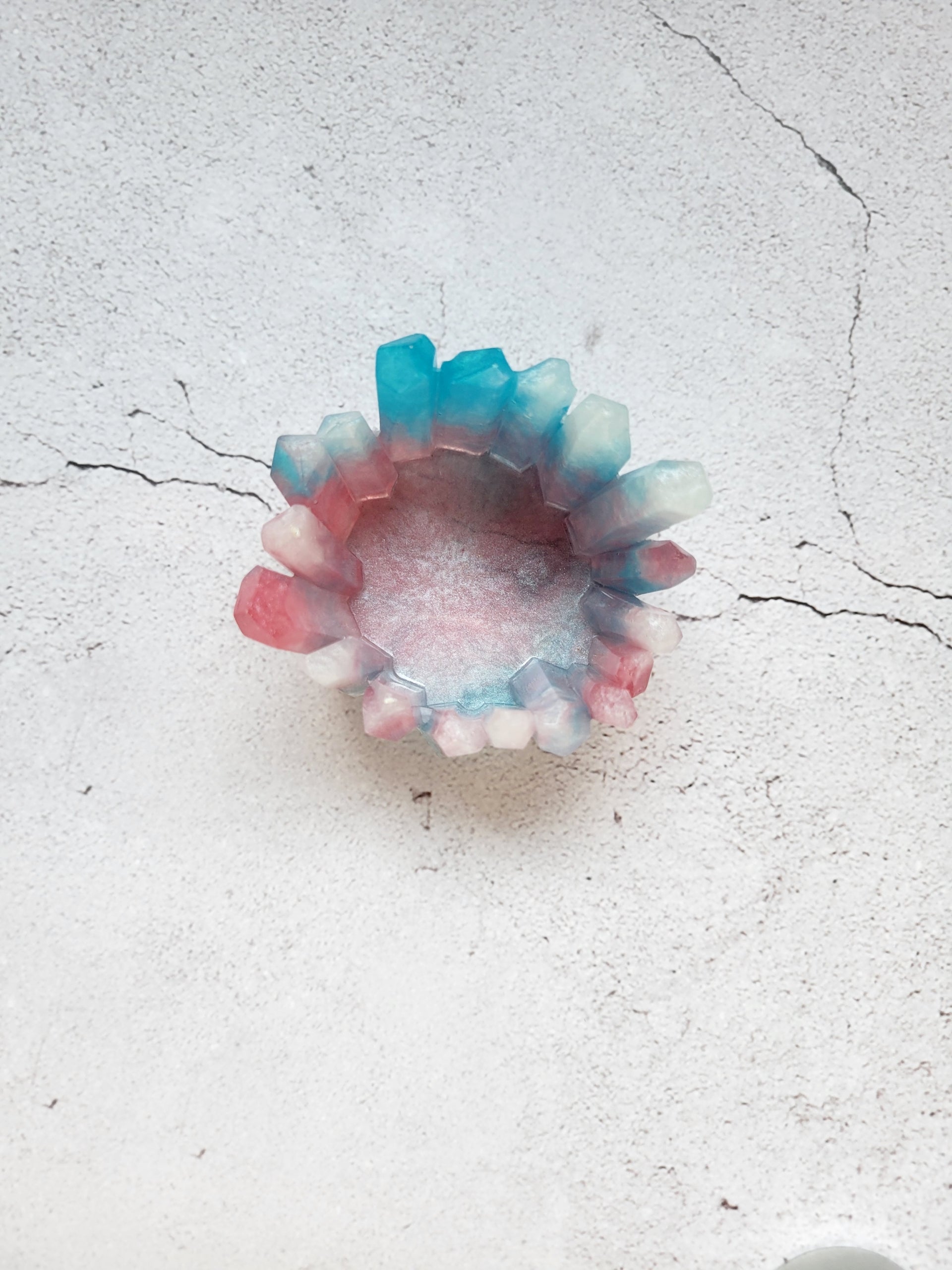 A top view of a tealight candle holder in the style of crystals in various heights. It's a mix of white, blue, pinks. 
