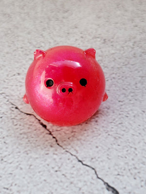 A small round pig figure with black painted eyes and nose. It's a bright reddish pink color.