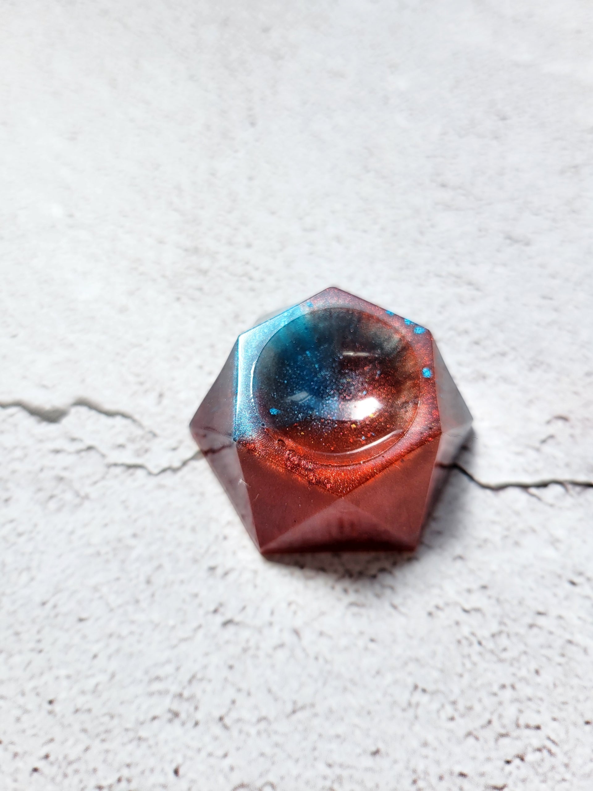 A side view of a hexagonal stand for dice or tabletop familiar. It is red and blue.