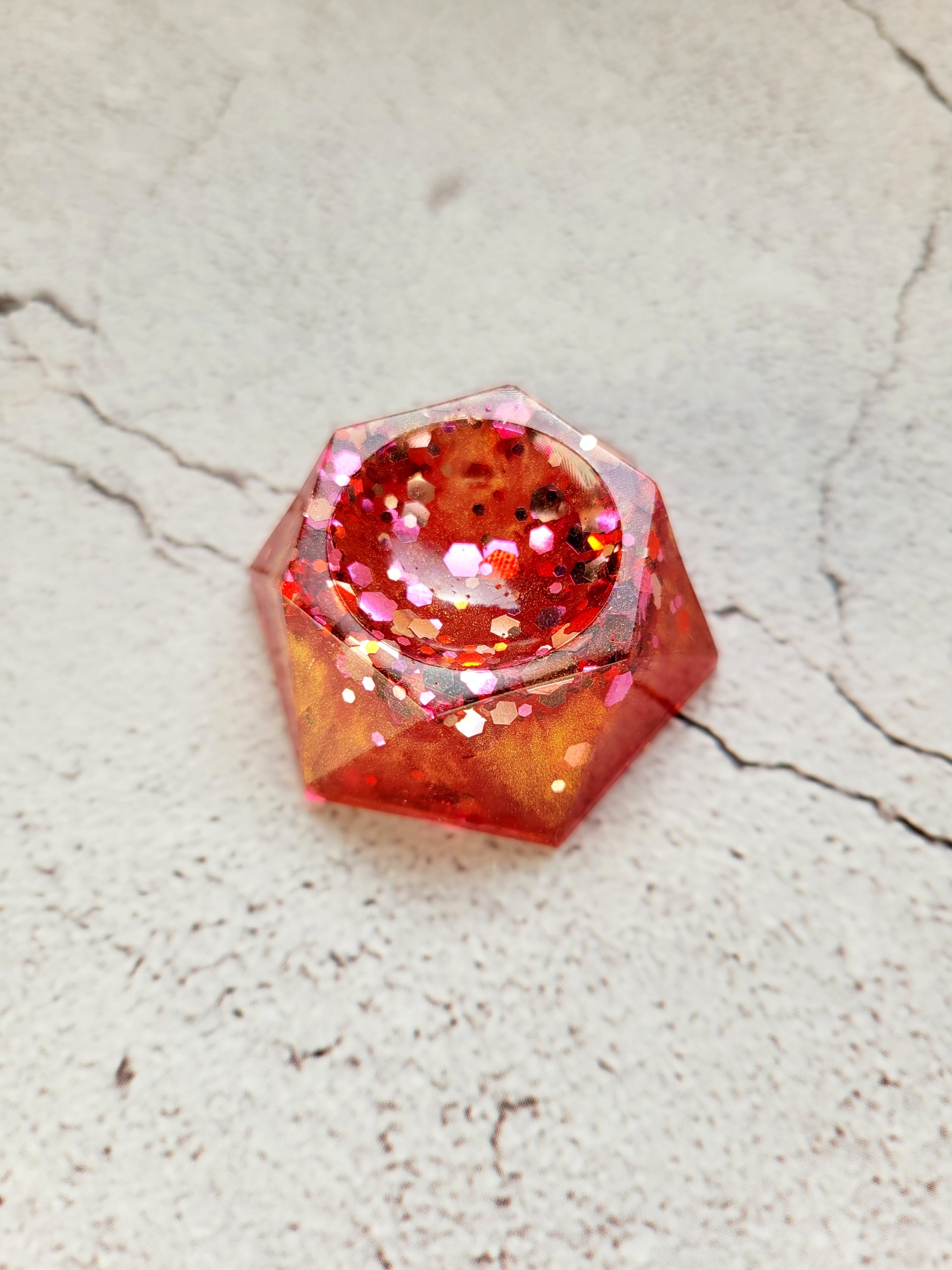 A side view of a hexagonal stand for dice or tabletop familiars. It's red and orange with glitter.