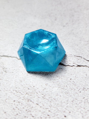 A side view of a hexagonal stand that holds a die or tabletop familiar. It's crystal blue.