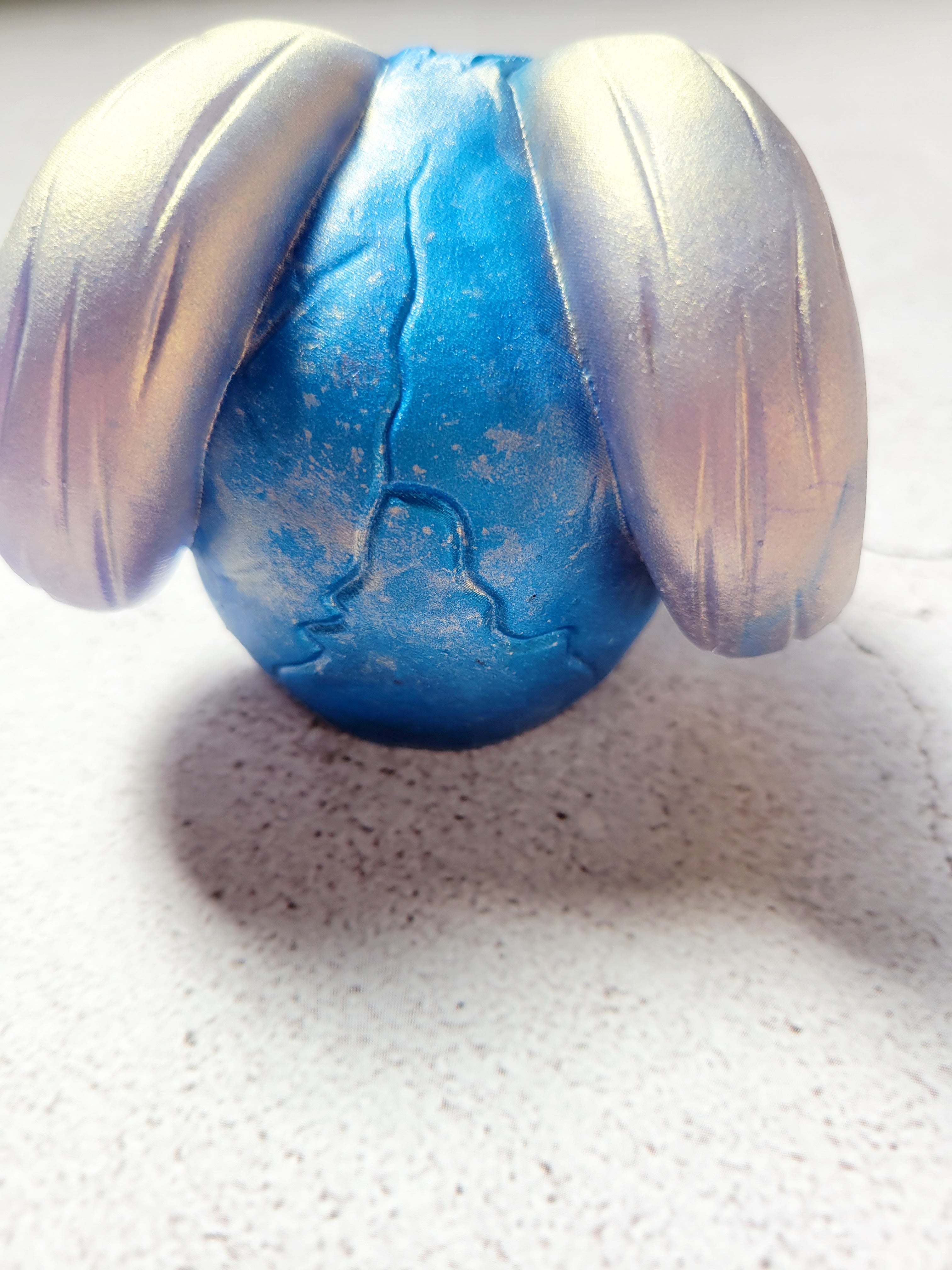 A back view of a skull with curved horns. it's teeth and horns are silver. The skull is blue. There is a textured crack in the back.