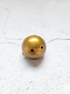 A small round penguin figure with painted black eyes. It's gold in color.