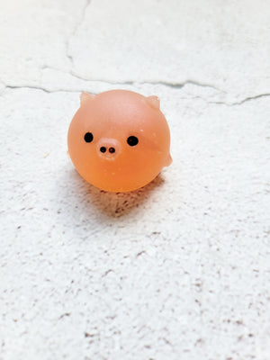 A small round pig figure with black painted eyes and nose. It's a matte finish. It's an orangey peach color.
