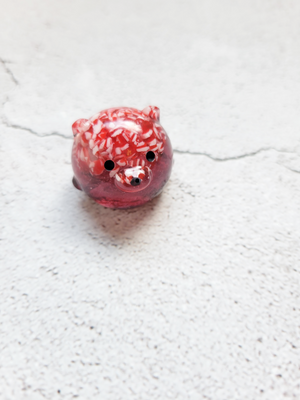A small round bear figure with black painted eyes and nose. It's red in color with the top half filled with peppermint candy crumbs.