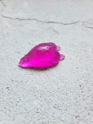 A side view of a sleeping penguin figure. It's bright pink with glitter. 
