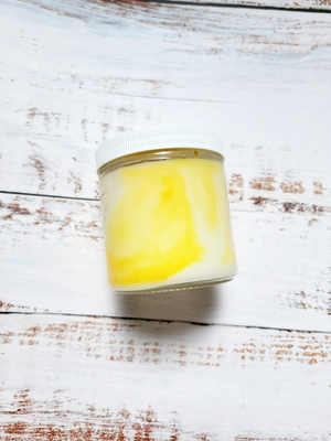 A side view of a 12oz marbled candle to show the yellow swirls in the wax. It's in a glass jar with a white lid. This candle is called Casual: Lemon Drop. It's scent profile is lemon, sugar.