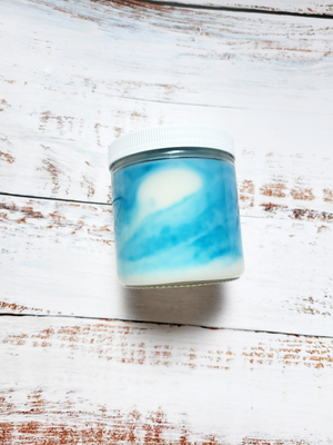 A 12oz marbled candle laying on its side to show the blue swirls in the wax. It has a white lid and glass jar. This candle is called Casual: Fruit Punch. It's scent notes are citrus, apple, coconut.