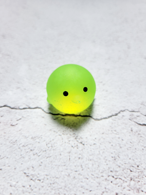 A small round penguin figure with black painted eyes. It's bright neon yellow/green.
