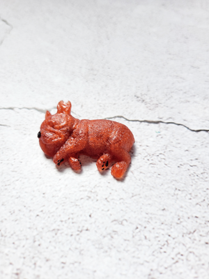 A sleeping dog figure with black painted nose and paws. He's a deep copper color.
