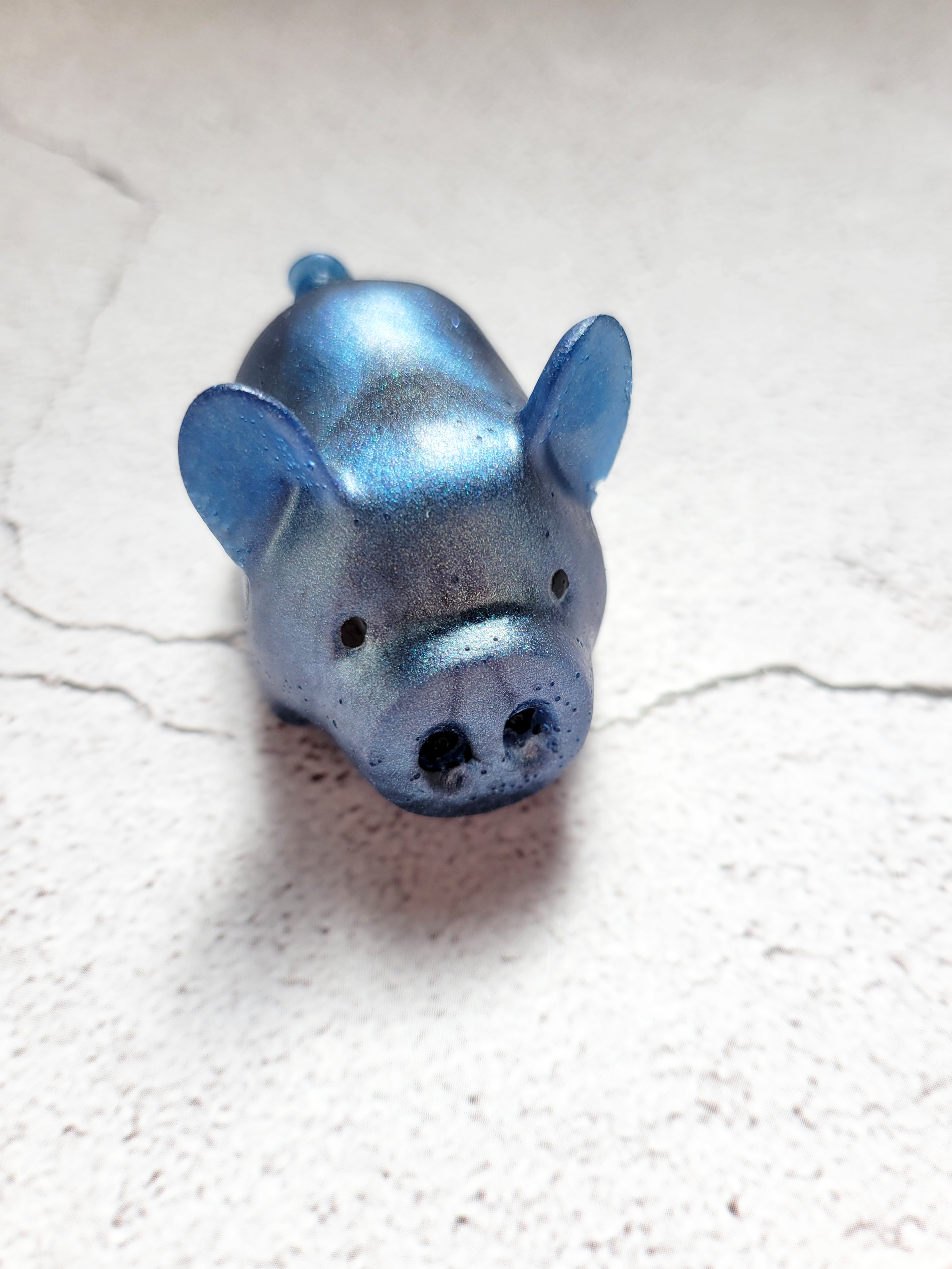 A front view of a fat pig figure. He's got black painted eyes and nostrils. He's a deep blue color.
