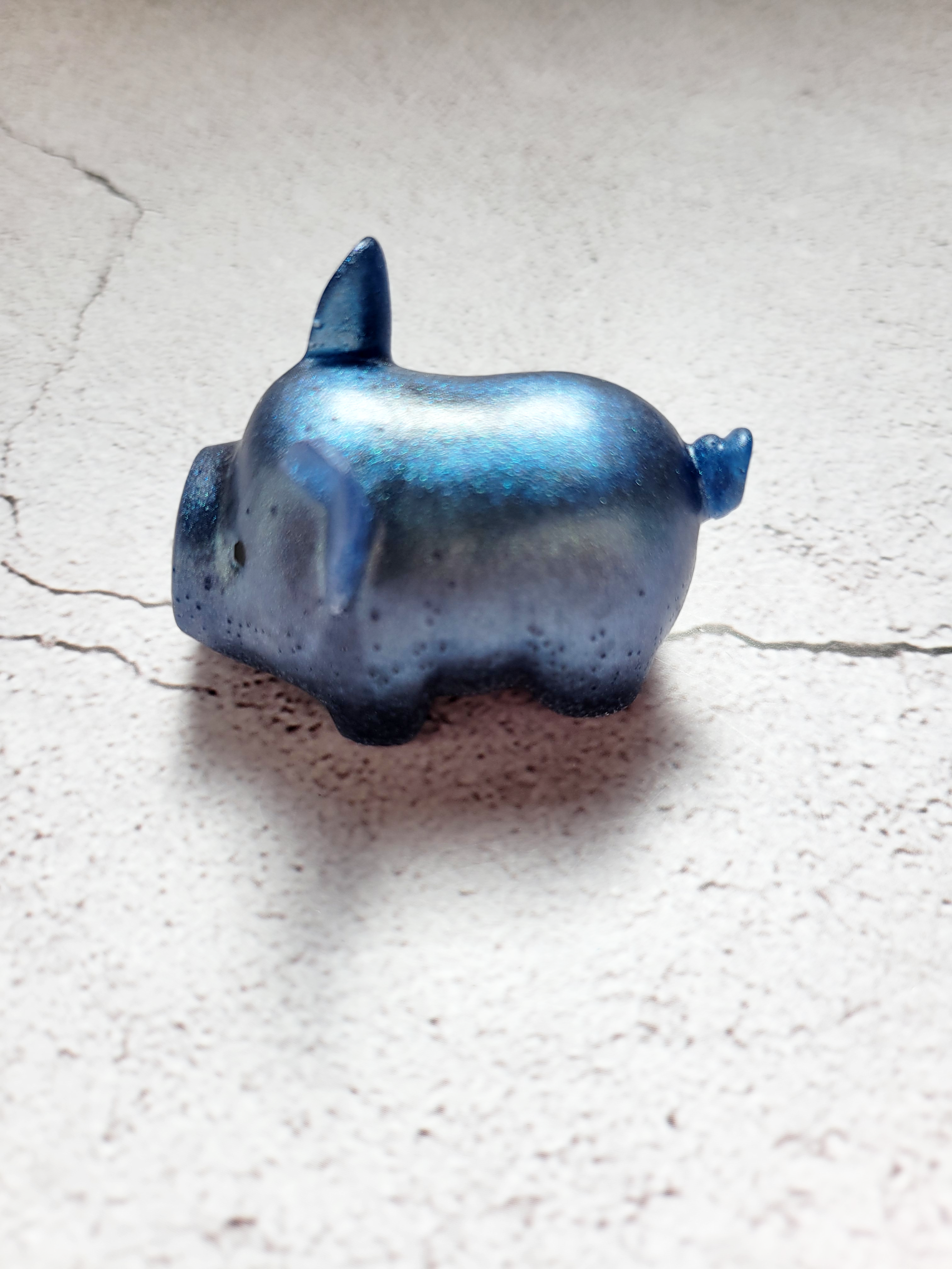 A side view of a fat pig figure. He's got black painted eyes and nostrils. He's a deep blue color.