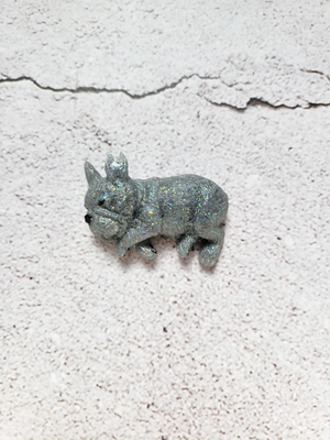 A small resin dog, sleeping on its side with black painted nose and eyes. It's dark gray with glitter.