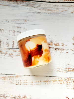 A 12oz marbled candle on its side to show the brown swirls in the wax. It's in a glass jar with a white lid.