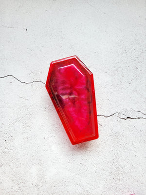 a resin made dice coffin, closed lid, in red and blacks