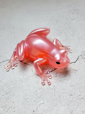 a resin made frog with black painted eyes. its body is a shimmering coral/pink color. Front view