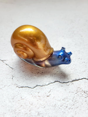 a resin made snail, front view. Body is blue and shell is copper