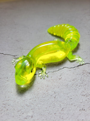 a resin made lizard with black painted eyes in clear neon yellow. front view