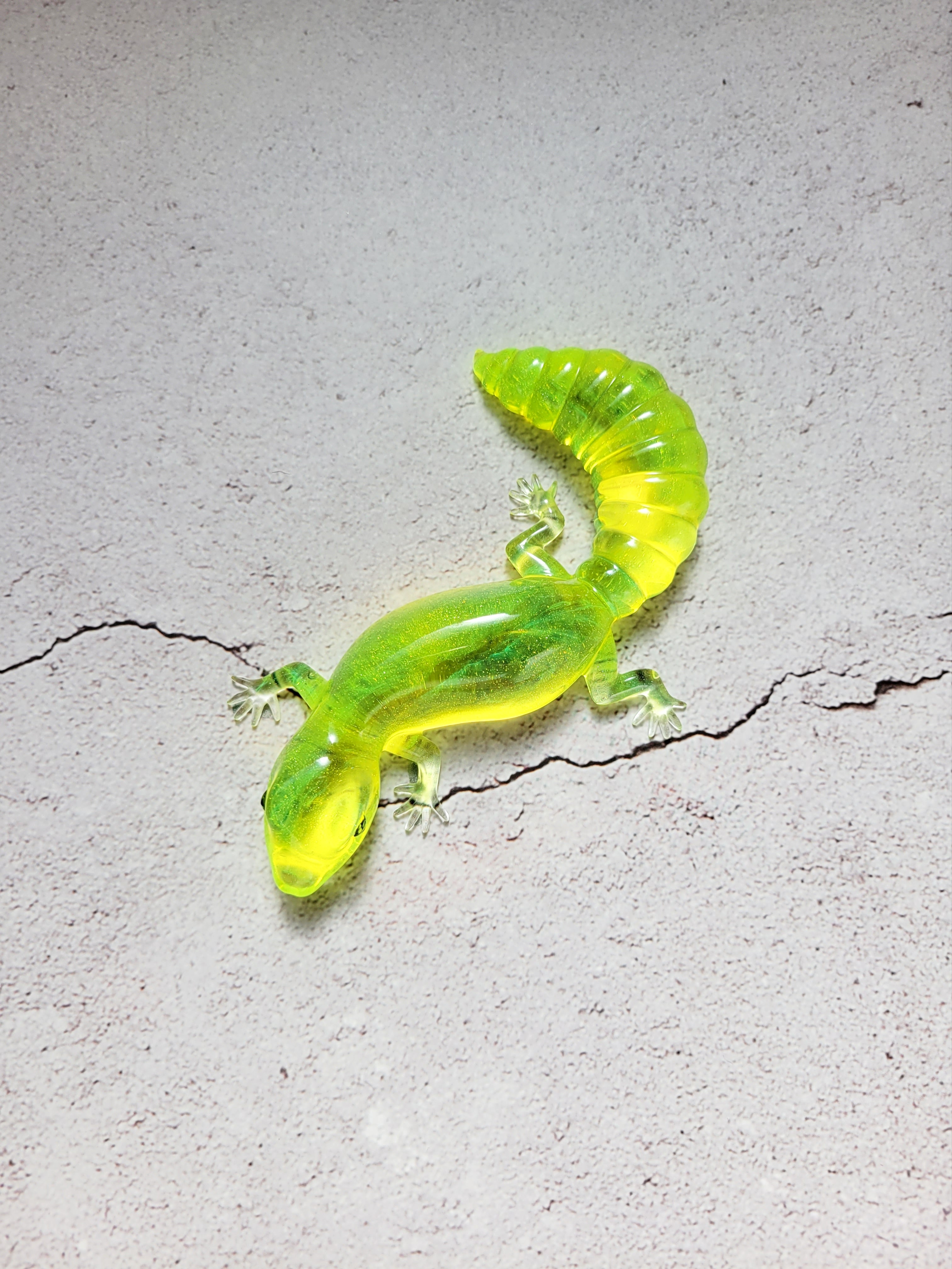 a resin made lizard with black painted eyes in clear neon yellow. top view
