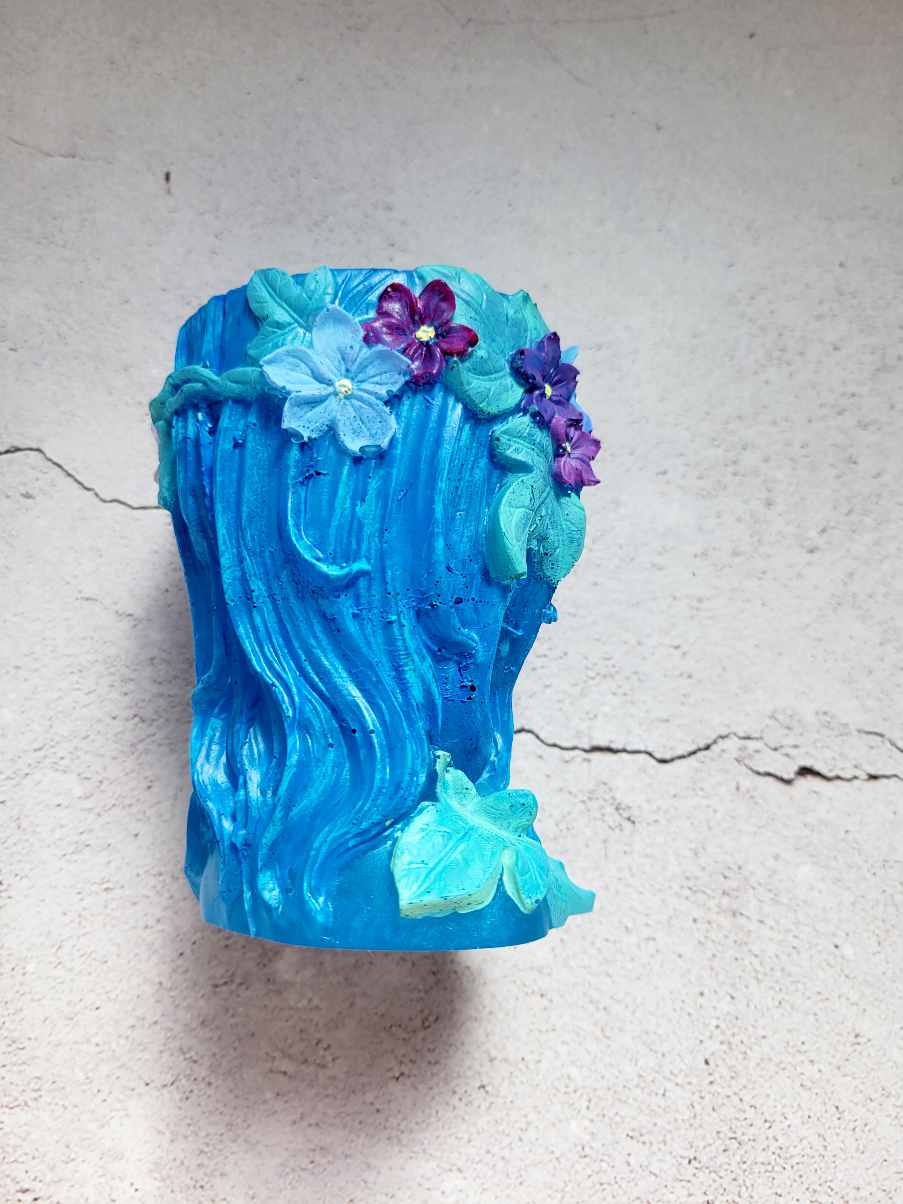 a resin made female ancient statue bust, blue in color with painted leaves and flowers. side view