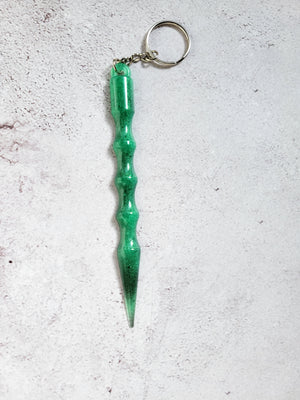 A defense keychain with silver chain and ring hoop. It's green with black tip.